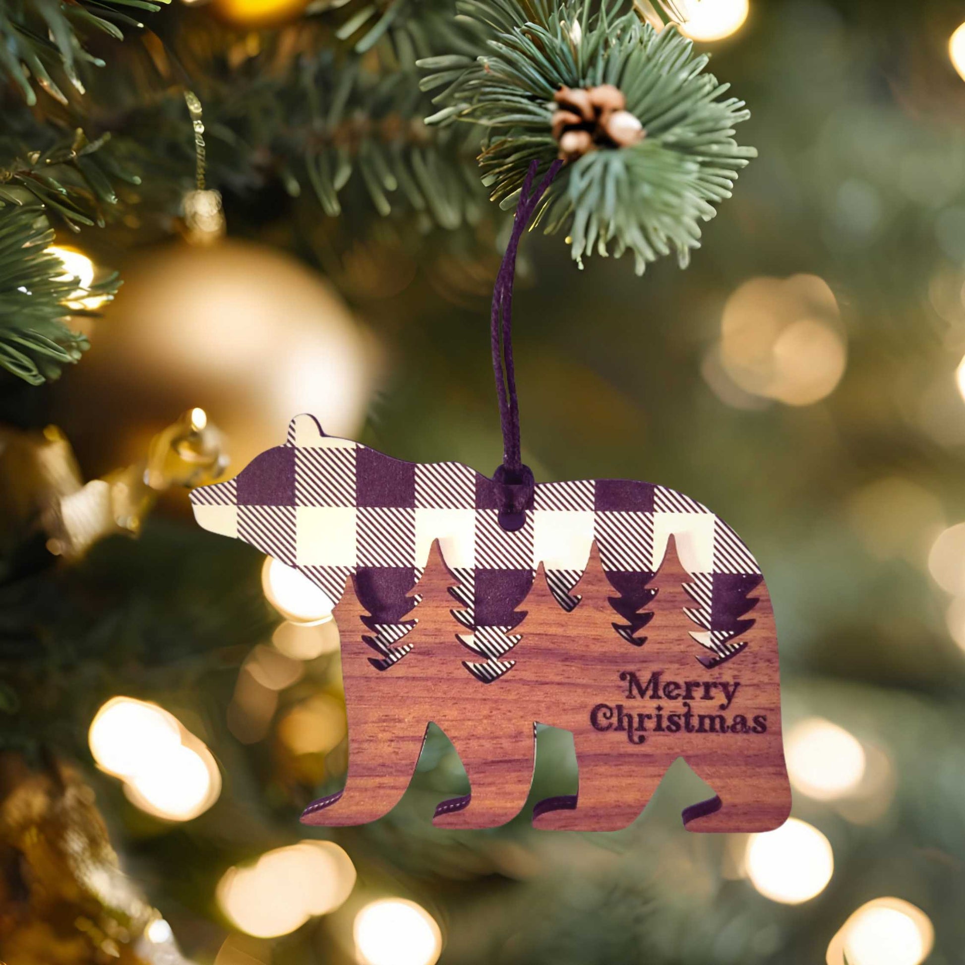 Wooden bear ornament with plaid pattern and 'Merry Christmas' text hanging on a Christmas tree.